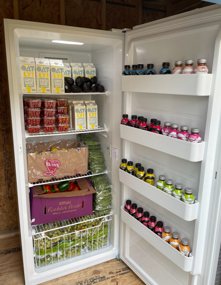 An open fridge with vegetables, milk, and other produce.